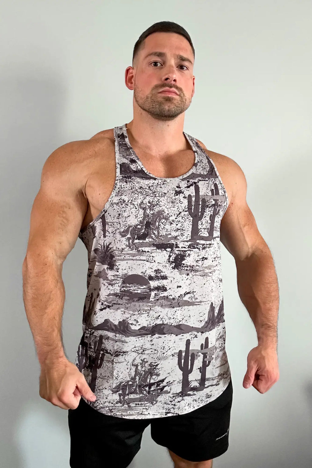 Graphic muscle stringer tank top in black and white featuring desert scene with cacti horses and mountains