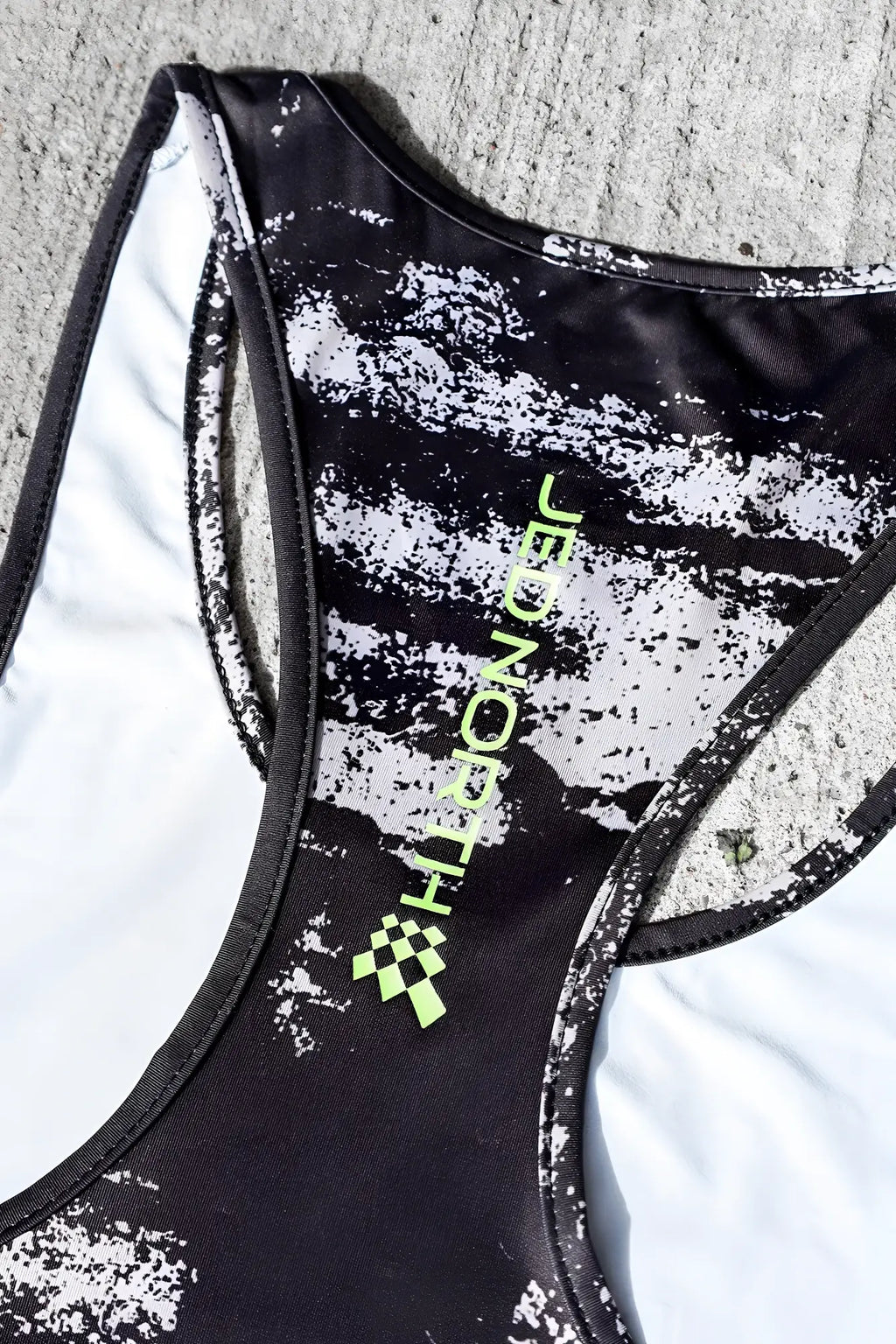Black and white speckled racerback tank top with neon green jed north branding featuring silver brush strokes design