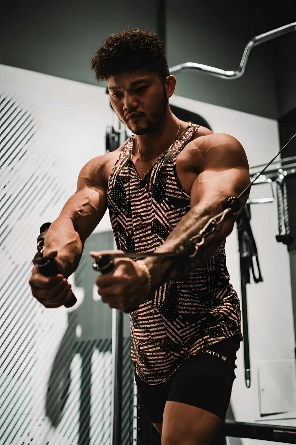 A man wearing a black and white geometric patterned graphic muscle stringer tank top with mesh texture usa flag design