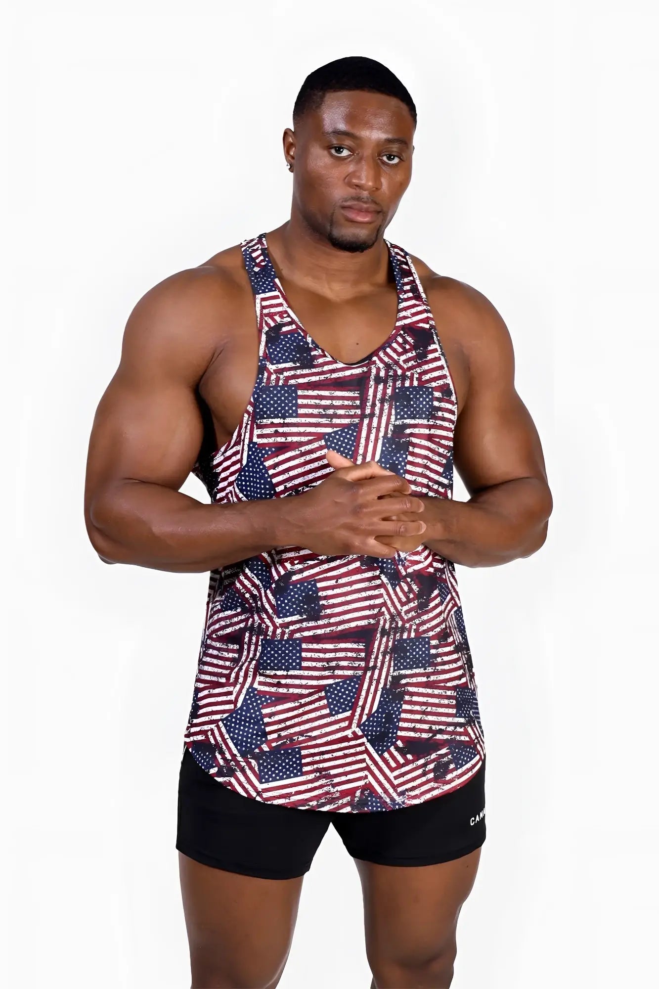 A man wearing a sleeveless graphic muscle stringer with an all-over USA flag pattern in red white and blue