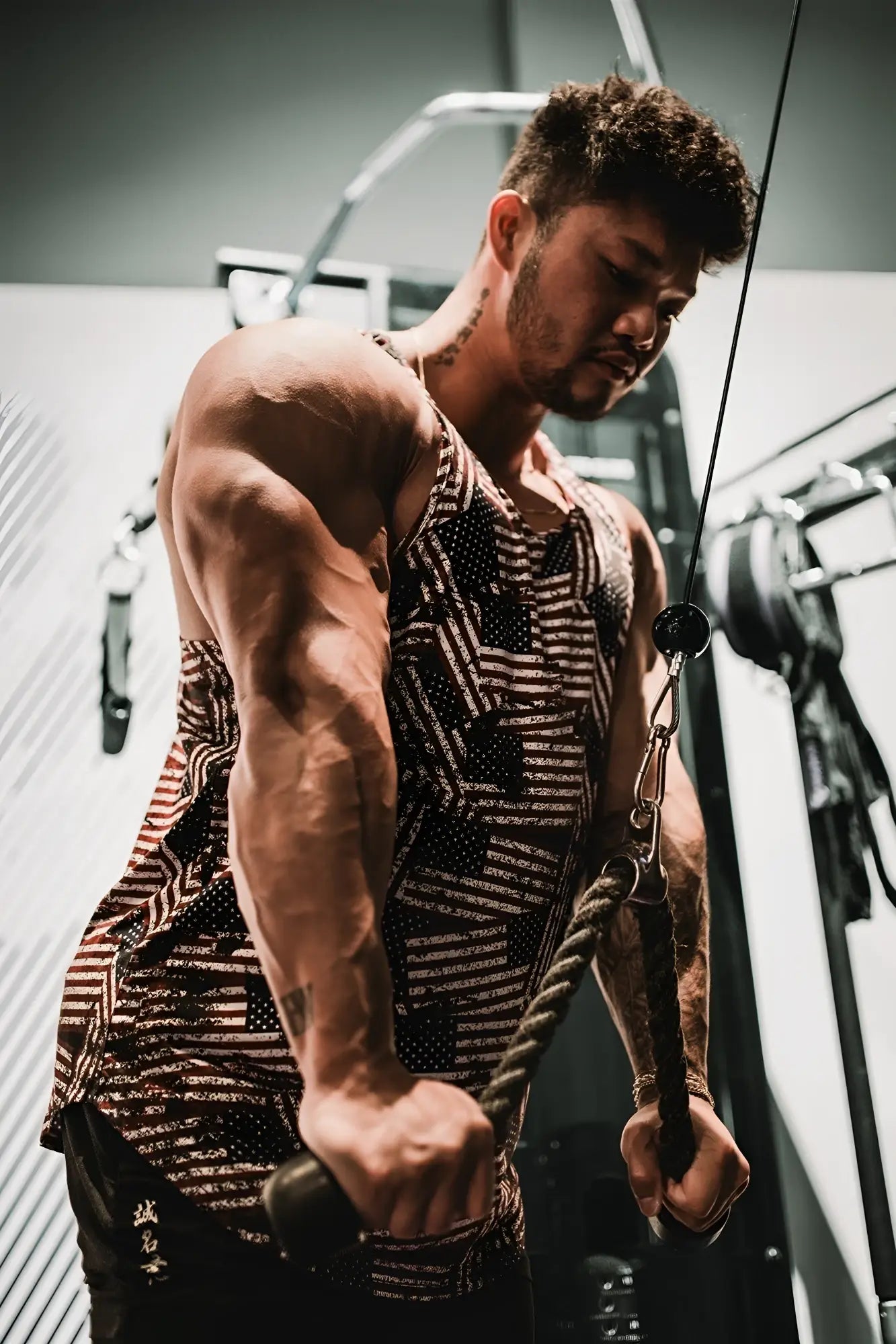Muscular man wearing a black and white patterned graphic muscle stringer usa flag tank top exercising