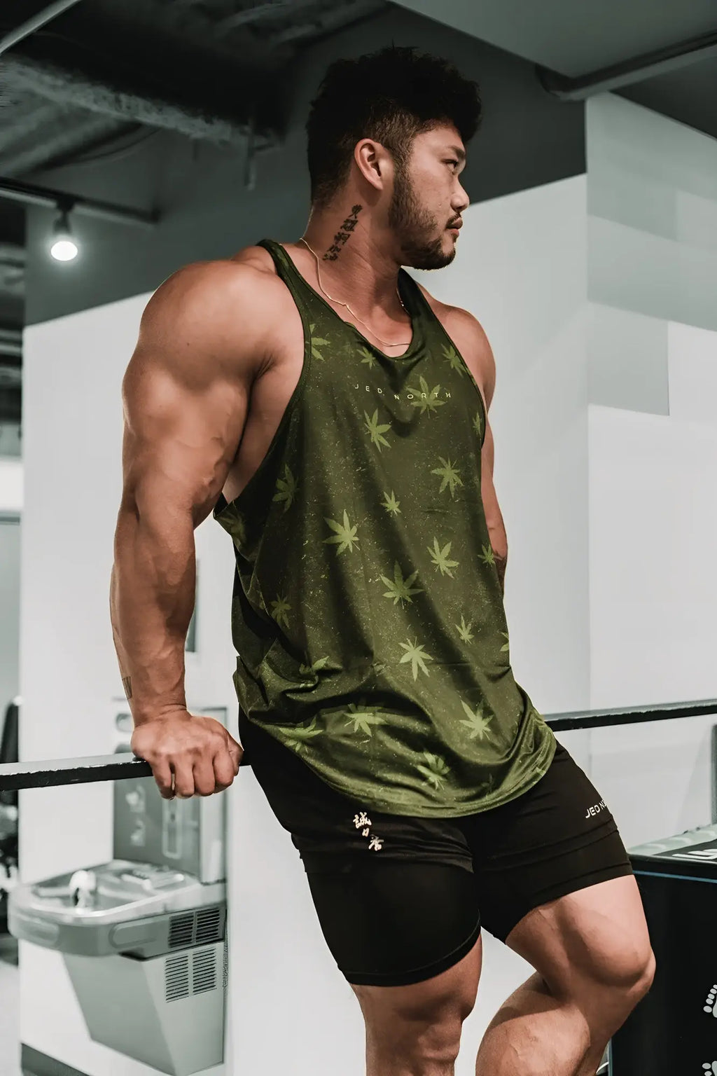 Olive green graphic muscle stringer tank top with subtle light green cannabis leaf pattern for casual wear