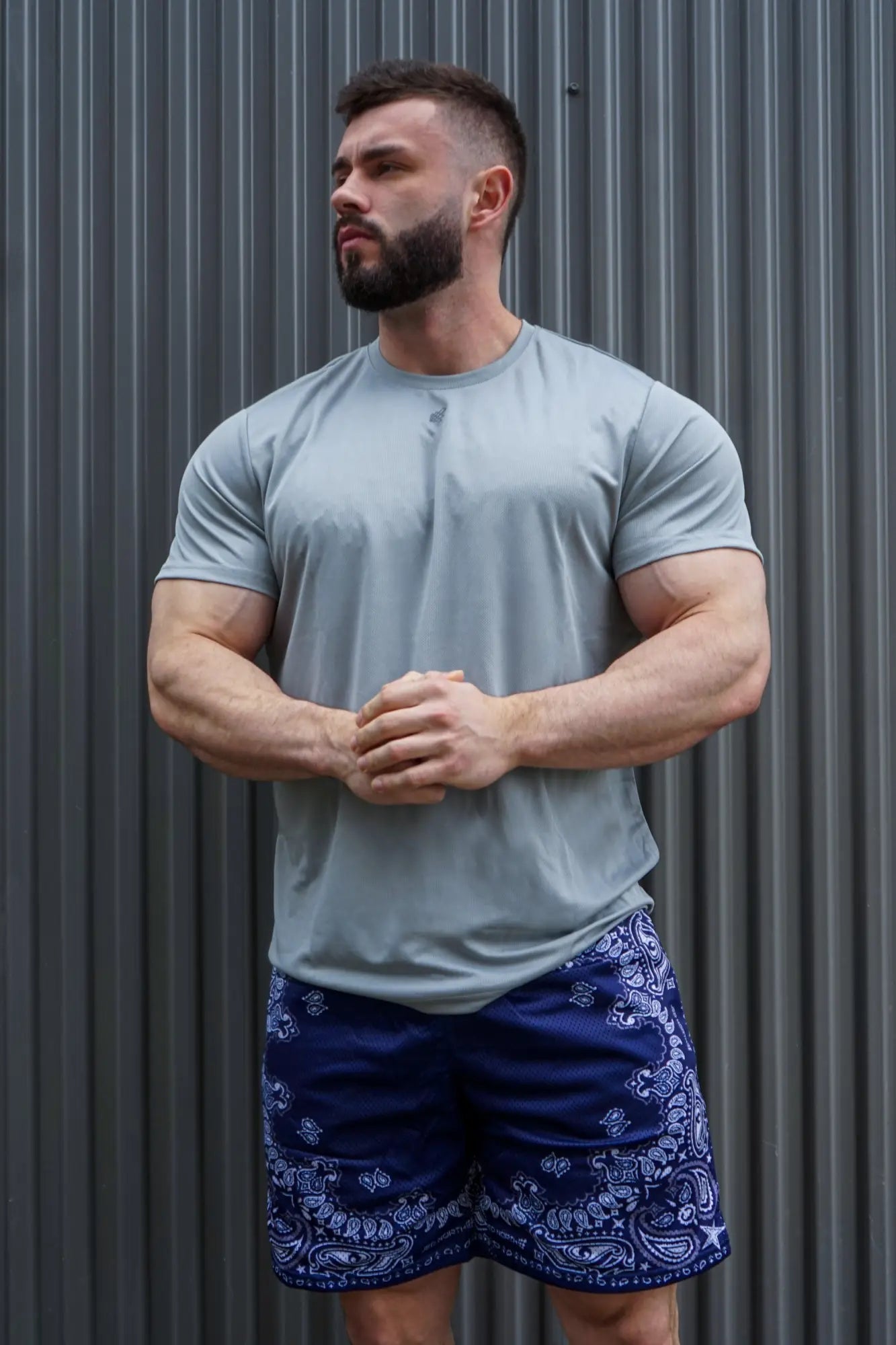 A man wearing jed north jersey mesh navy paisley 7.5 inch gym shorts and a light gray henley shirt