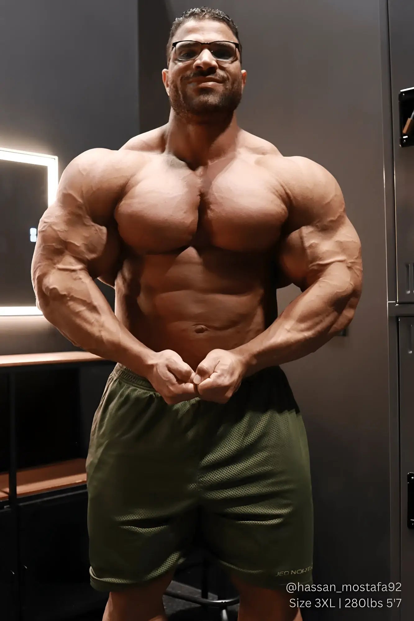 A muscular man wearing olive green Jed North Jersey mesh 7.5 inch gym shorts made for athletic performance