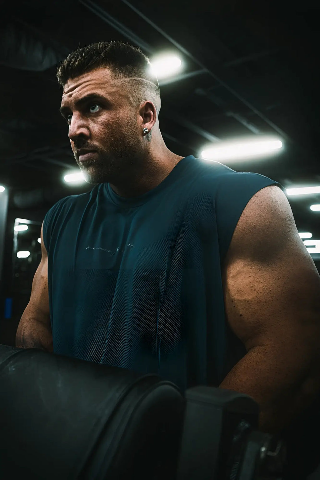 A muscular man wearing a navy blue sleeveless JN Active Muscle Tee made of breathable athletic fabric