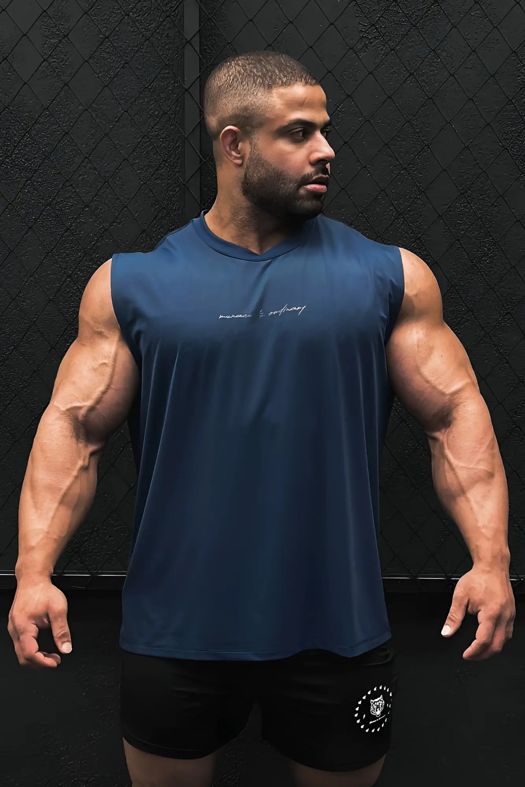 A navy blue sleeveless athletic tank top with a subtle white cursive logo across the chest for active use