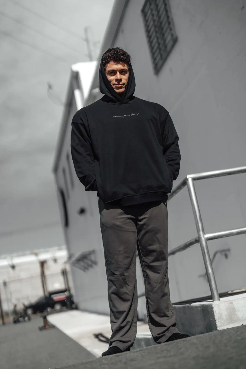 Black hooded sweatshirt with subtle white cursive embroidery across the chest paired with gray Jed North Lax straight cut joggers