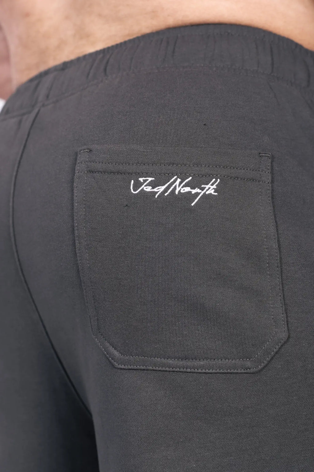Back side of black jed north lax straight cut joggers featuring subtle embroidered logo on the back pocket