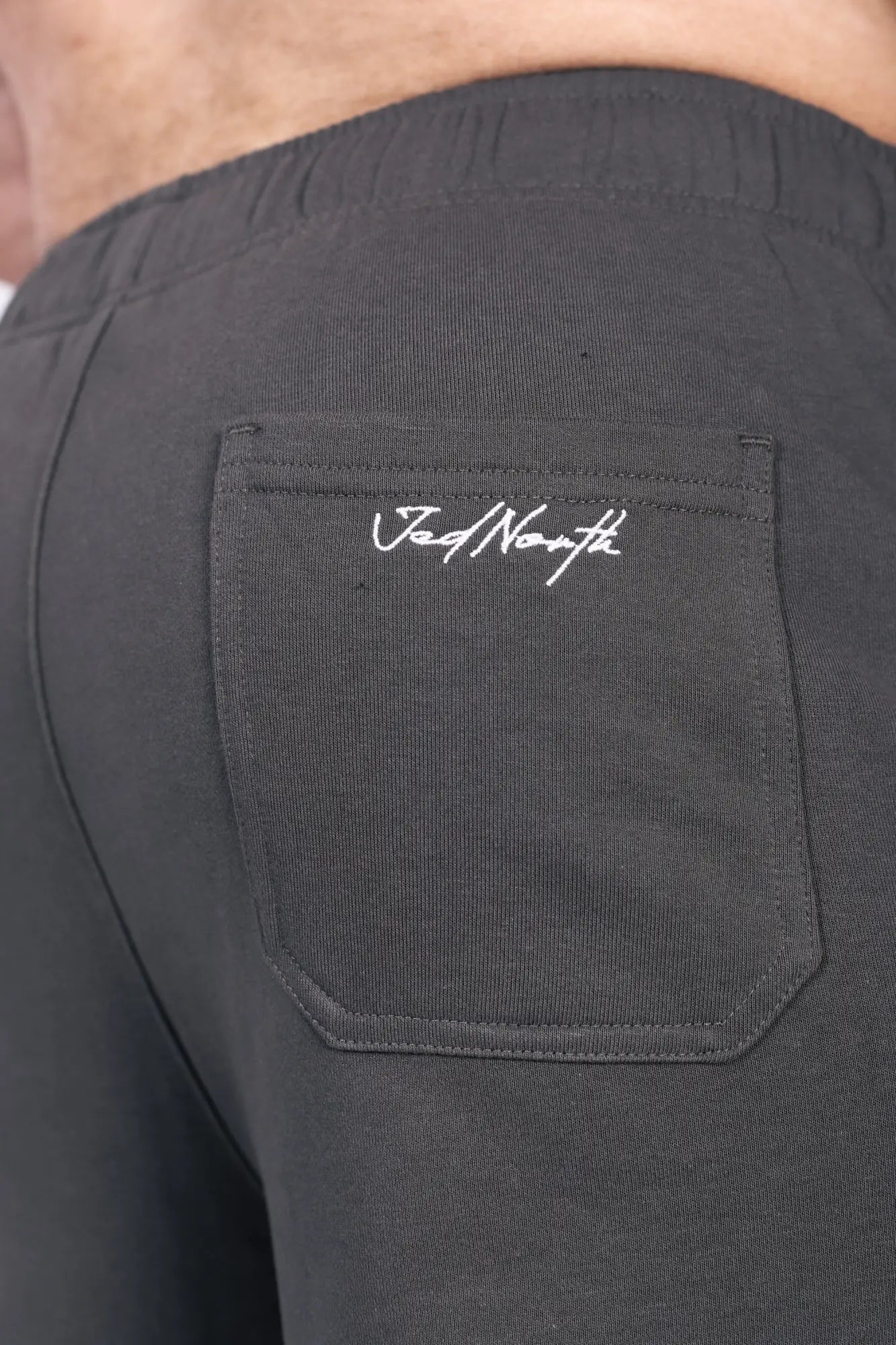 Back side of black jed north lax straight cut joggers featuring subtle embroidered logo on the back pocket