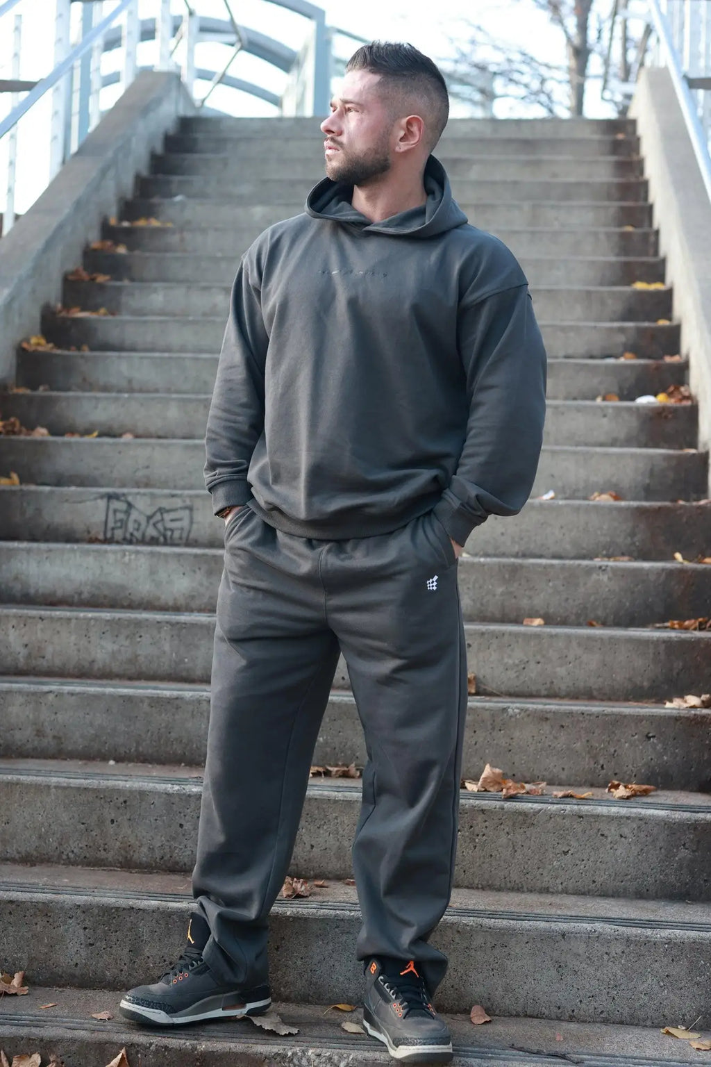 Dark gray jed north lax straight cut joggers with a subtle white emblem paired with a matching hooded sweatshirt