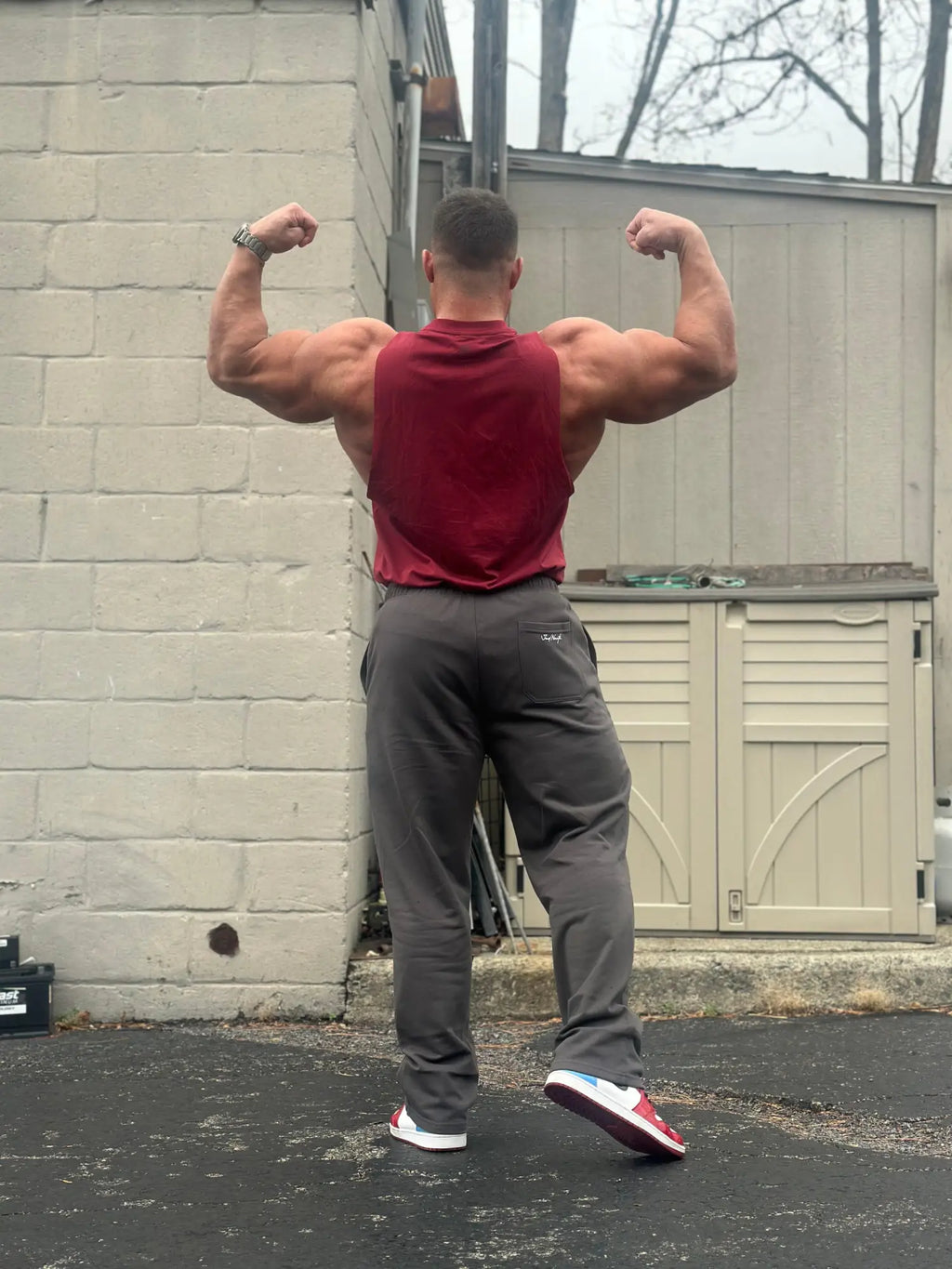 A muscular man wearing Jed North lax straight cut joggers in gray paired with a red sleeveless top