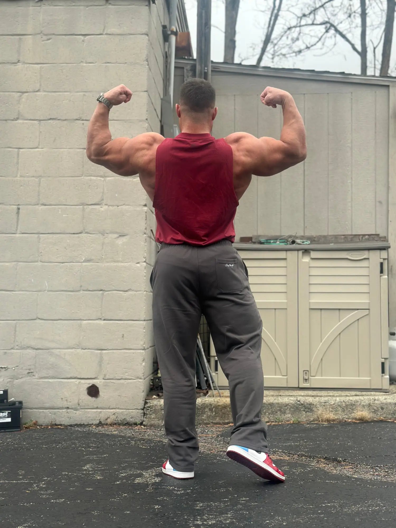 A muscular man wearing Jed North lax straight cut joggers in gray paired with a red sleeveless top