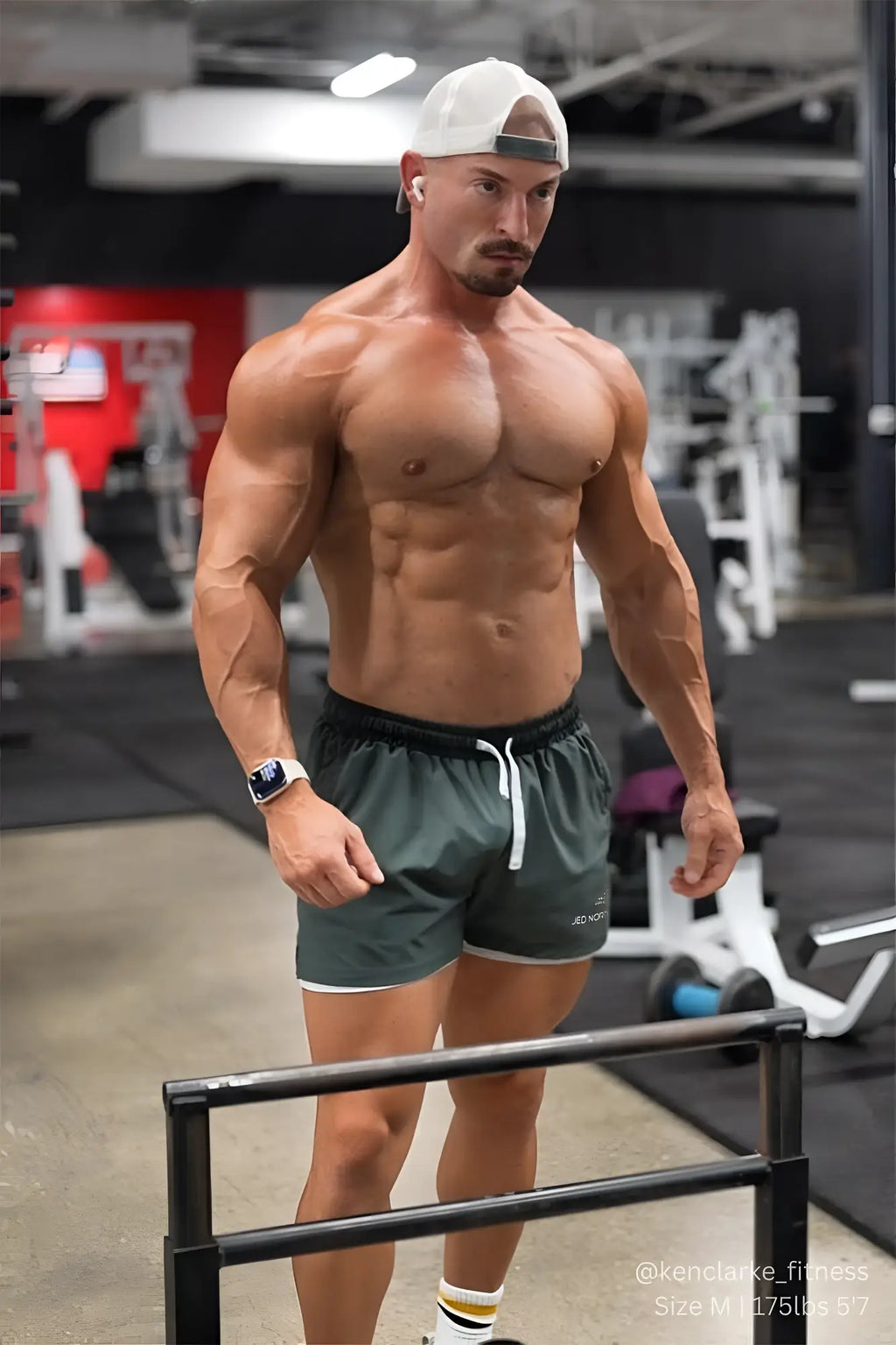 A muscular man wearing jed north men’s 2-in-1 active 5 inch training shorts 2.0 in olive with white trim