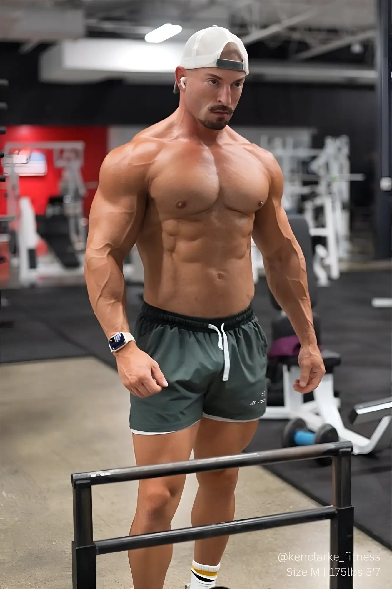 A muscular man wearing jed north men’s 2-in-1 active 5 inch training shorts 2.0 in olive with white trim