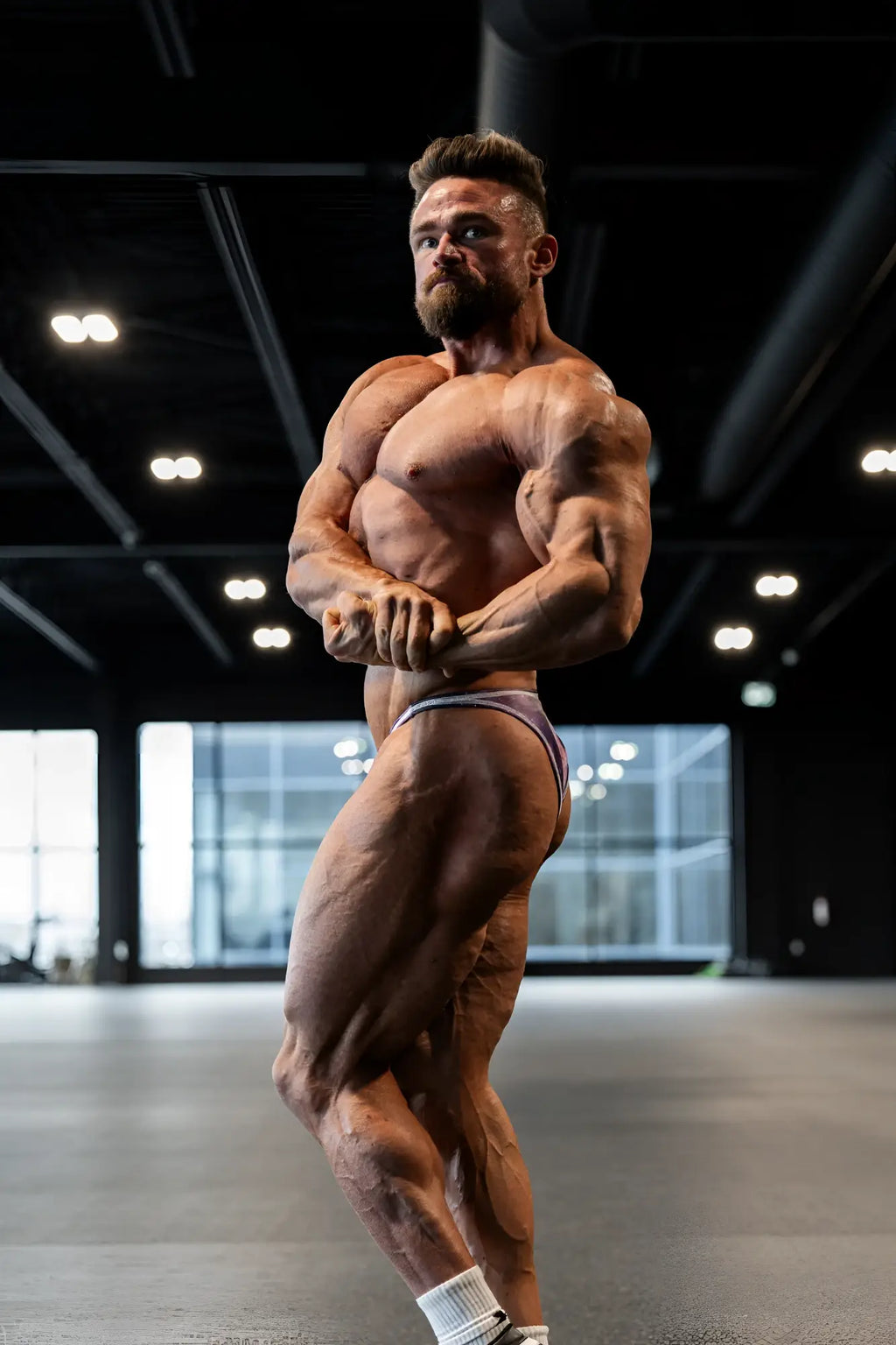 A muscular man wearing galaxy men’s bodybuilding posing trunks with minimalistic design for competition use