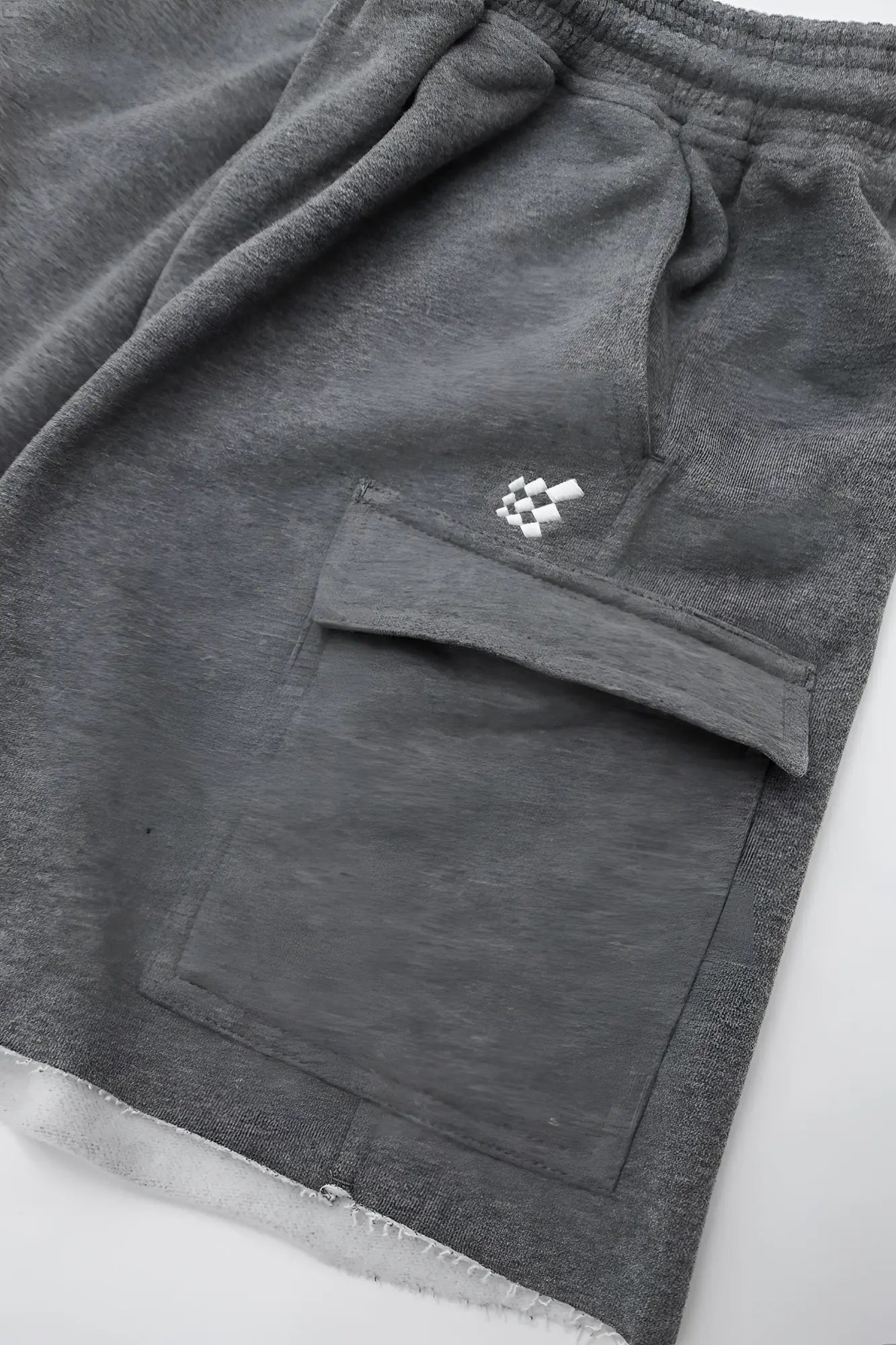 Men’s dark gray cargo sweat shorts with gray heathered fabric, white checkered pocket patch, and frayed hem