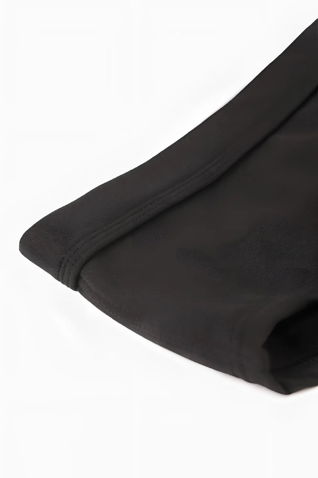 Black fabric with neat stitching along the hem of men’s classic physique posing trunks standard 4 inch side seam
