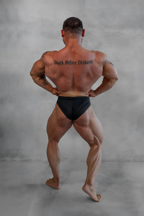 A muscular man wearing black men’s classic physique trunks with a 2 inch seam showcasing a sleek fit