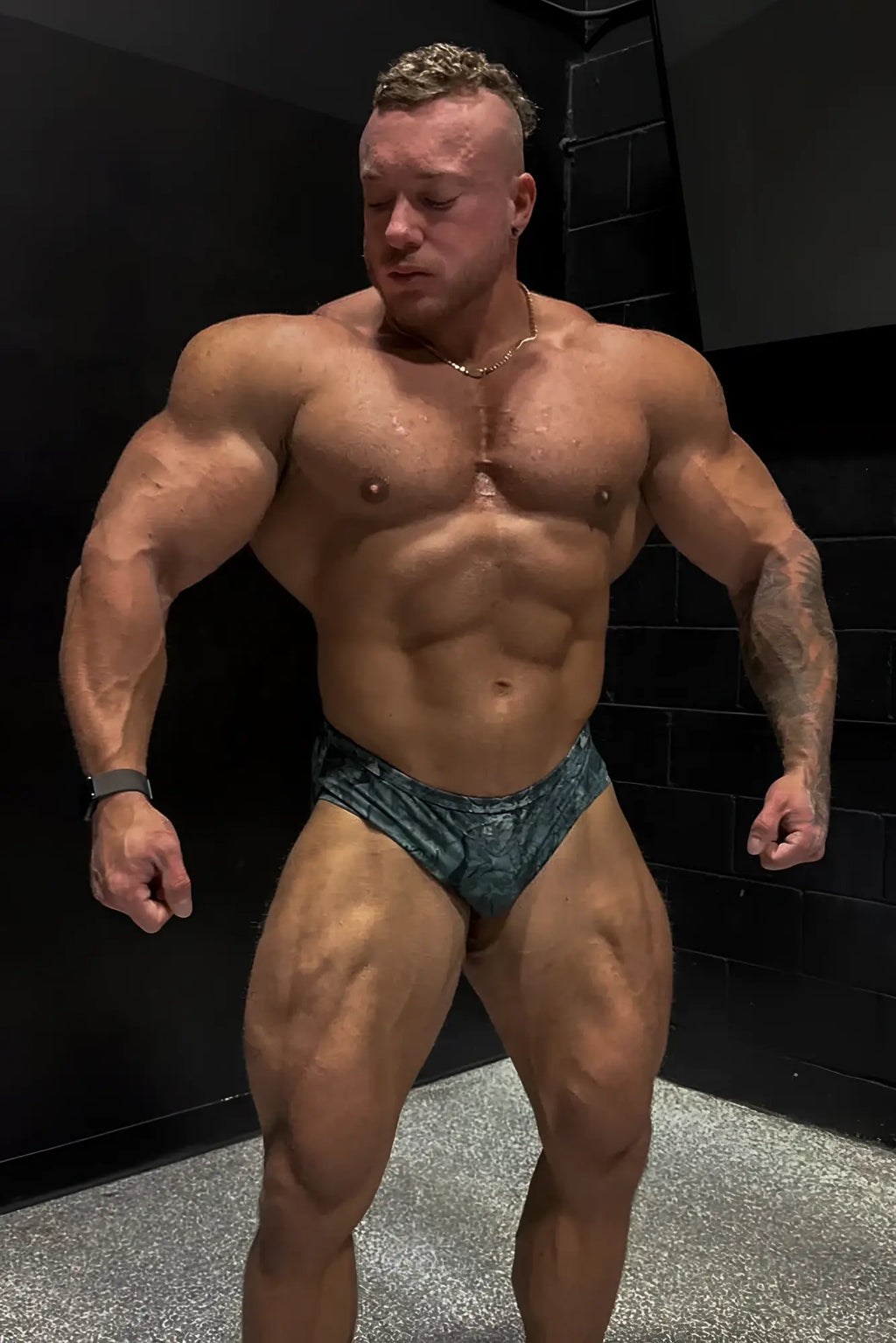 Muscular man wearing men’s classic physique trunks 2 inch seam in blue and black camo patterned briefs front view