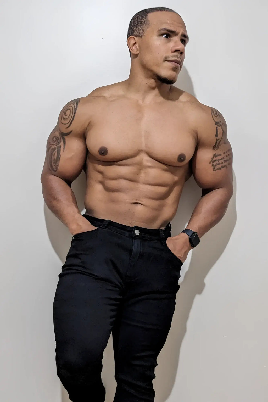 A muscular man with tattoos wearing black men’s fitted stretchy pants made of comfortable elastic material