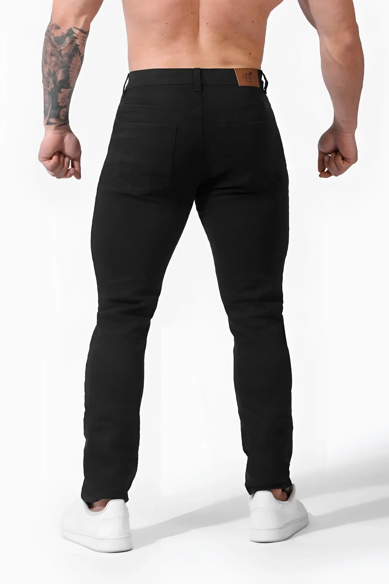 Men’s fitted stretchy black slim-fit denim jeans with brown leather belt loops and detailed stitching