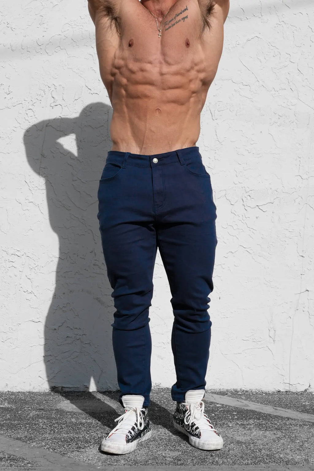 Men’s fitted stretchy navy slim-fit trousers with white button and subtle creases for a sleek look