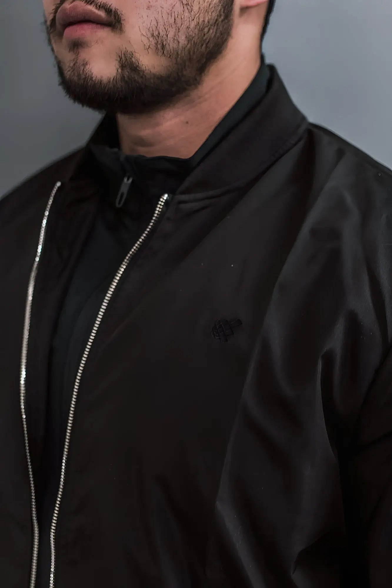 Men’s premium black bomber jacket with shiny silver zipper and subtle embroidered logo on the chest