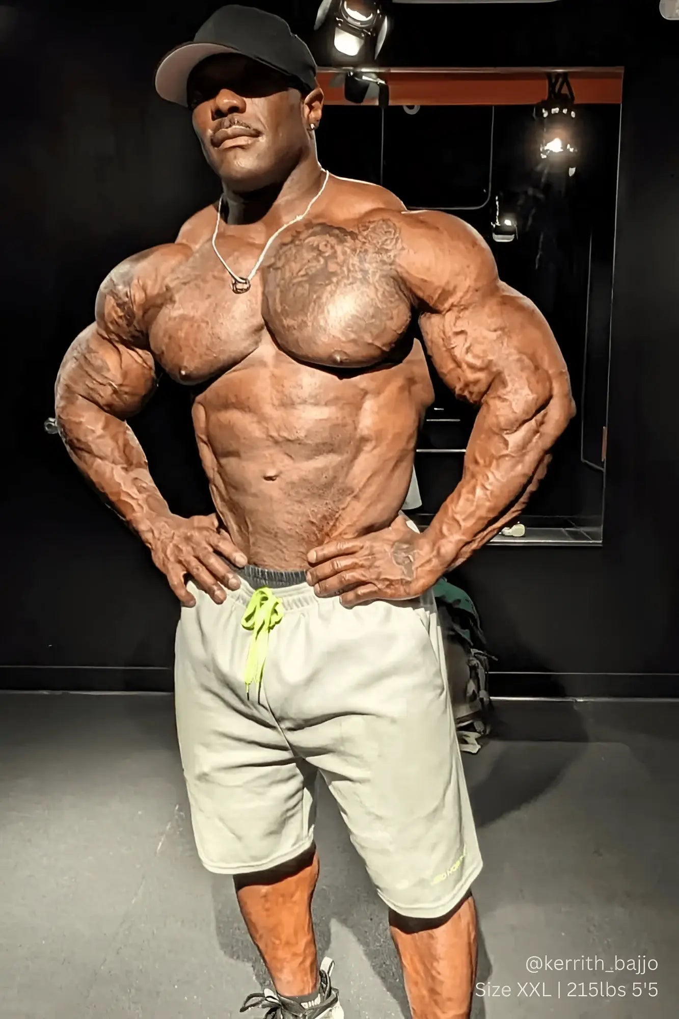 Muscular man wearing men’s pro mesh shorts 8 inch light gray with neon green drawstring and silver chain necklace