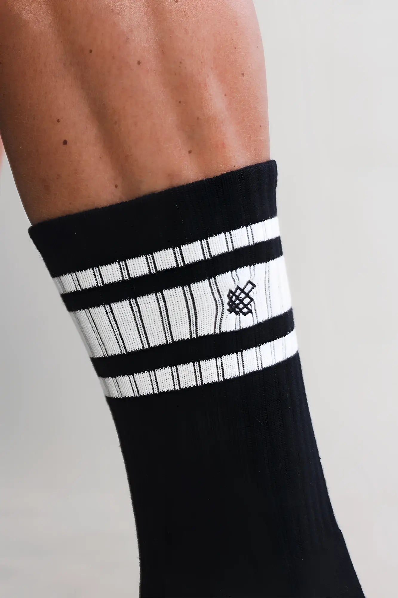 Men’s black striped crew socks with white horizontal stripes and a small black woven logo on the cuff