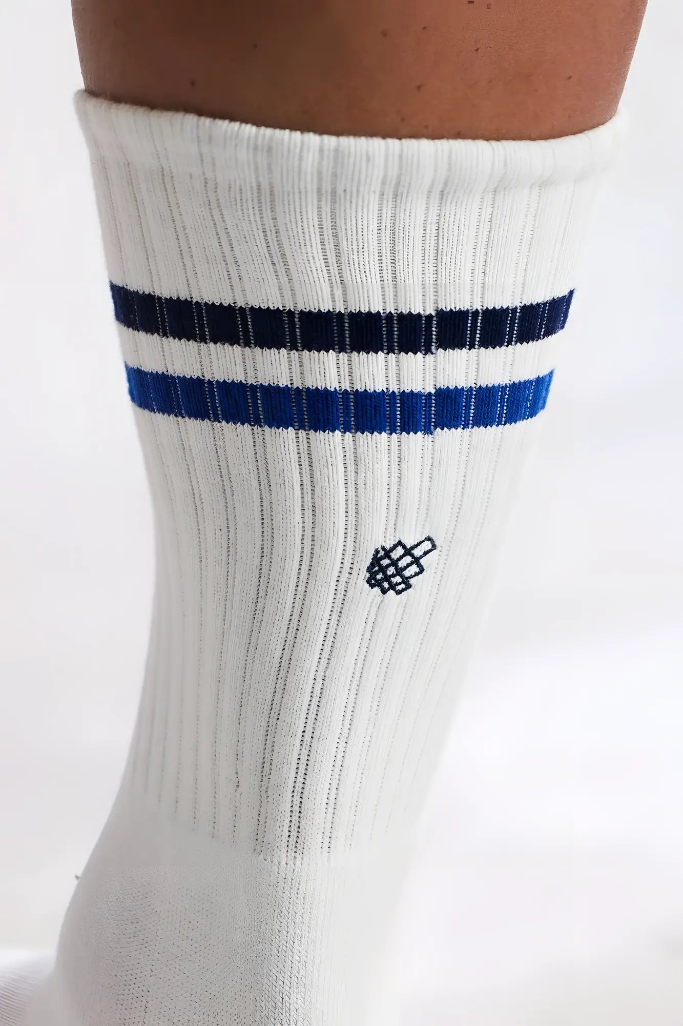 Men’s striped crew socks in white ribbed cotton with navy and royal blue stripes and a small black embroidered logo