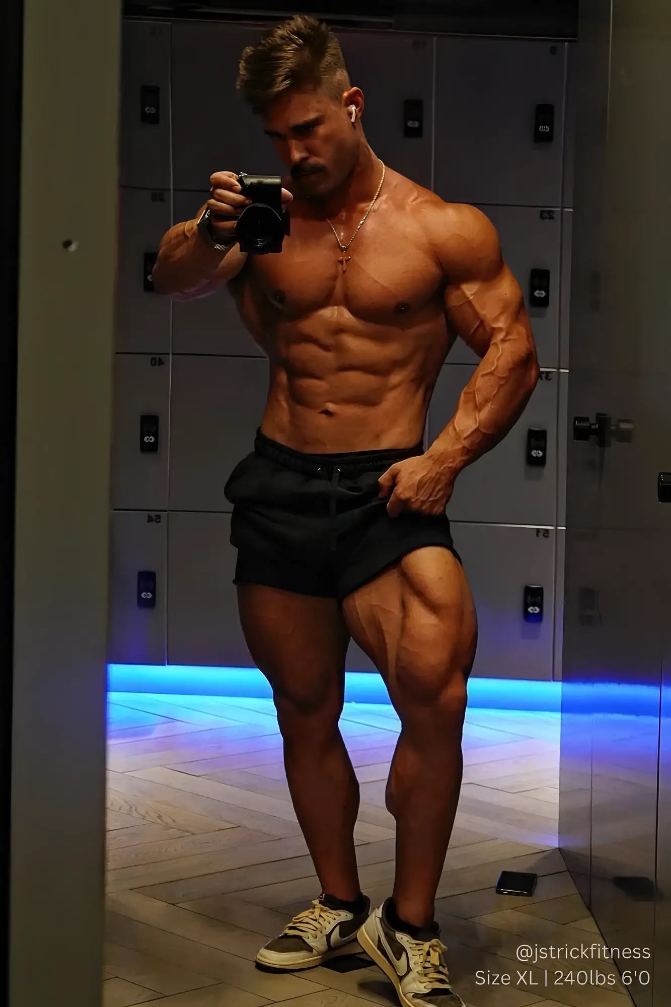 Muscular man wearing jed north motion 5 inch varsity sweat shorts in black with defined abs and legs in white sneakers