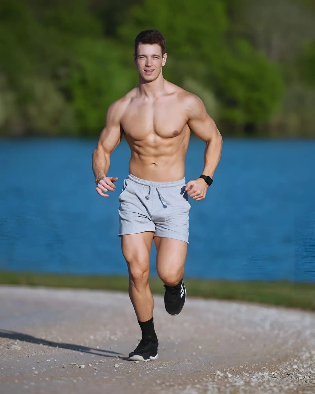 A man wearing jed north motion 5 inch varsity sweat shorts in gray paired with black adidas sneakers