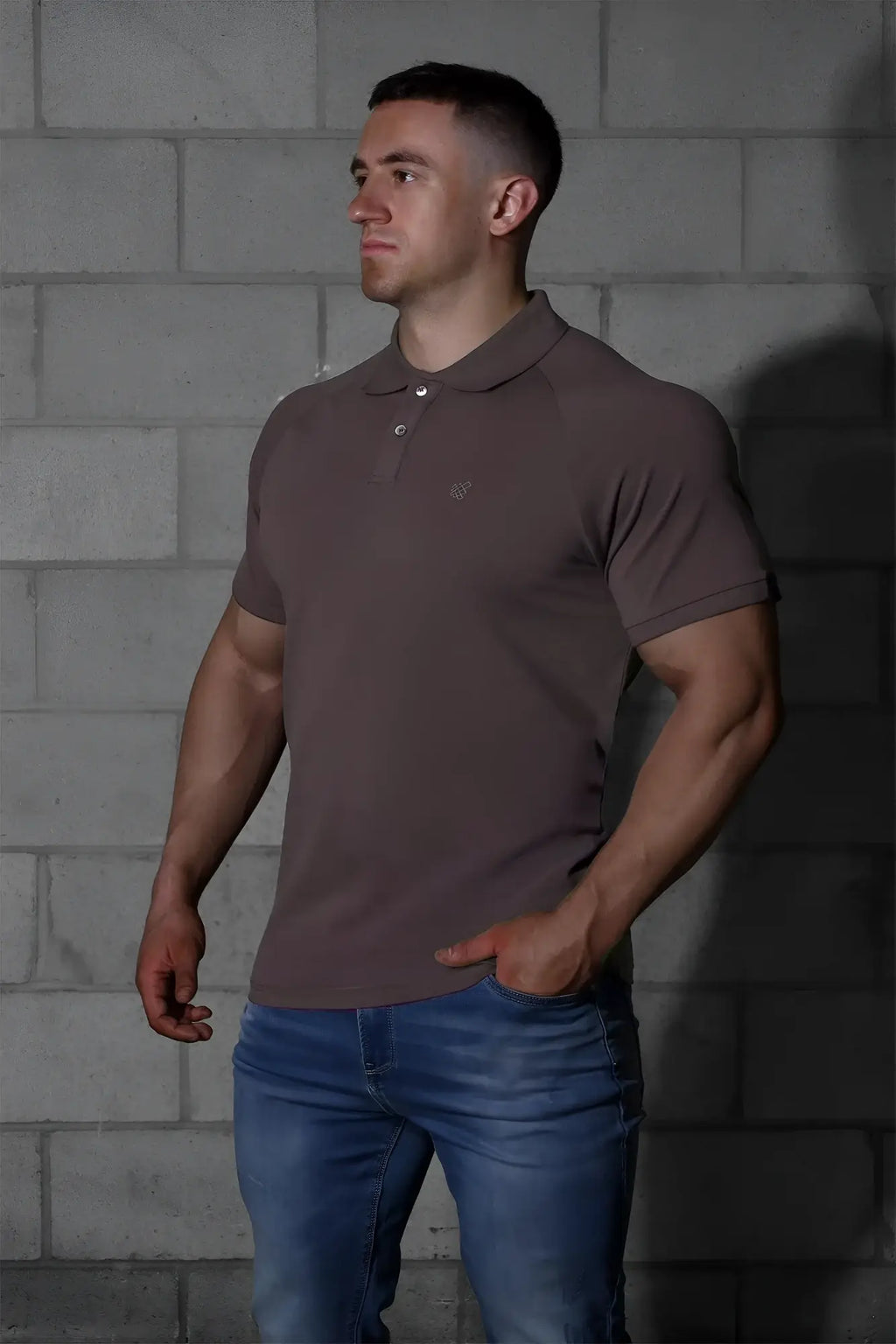 A man wearing a jed north muscle fit all day polo t shirt in dark gray with a small embroidered chest logo