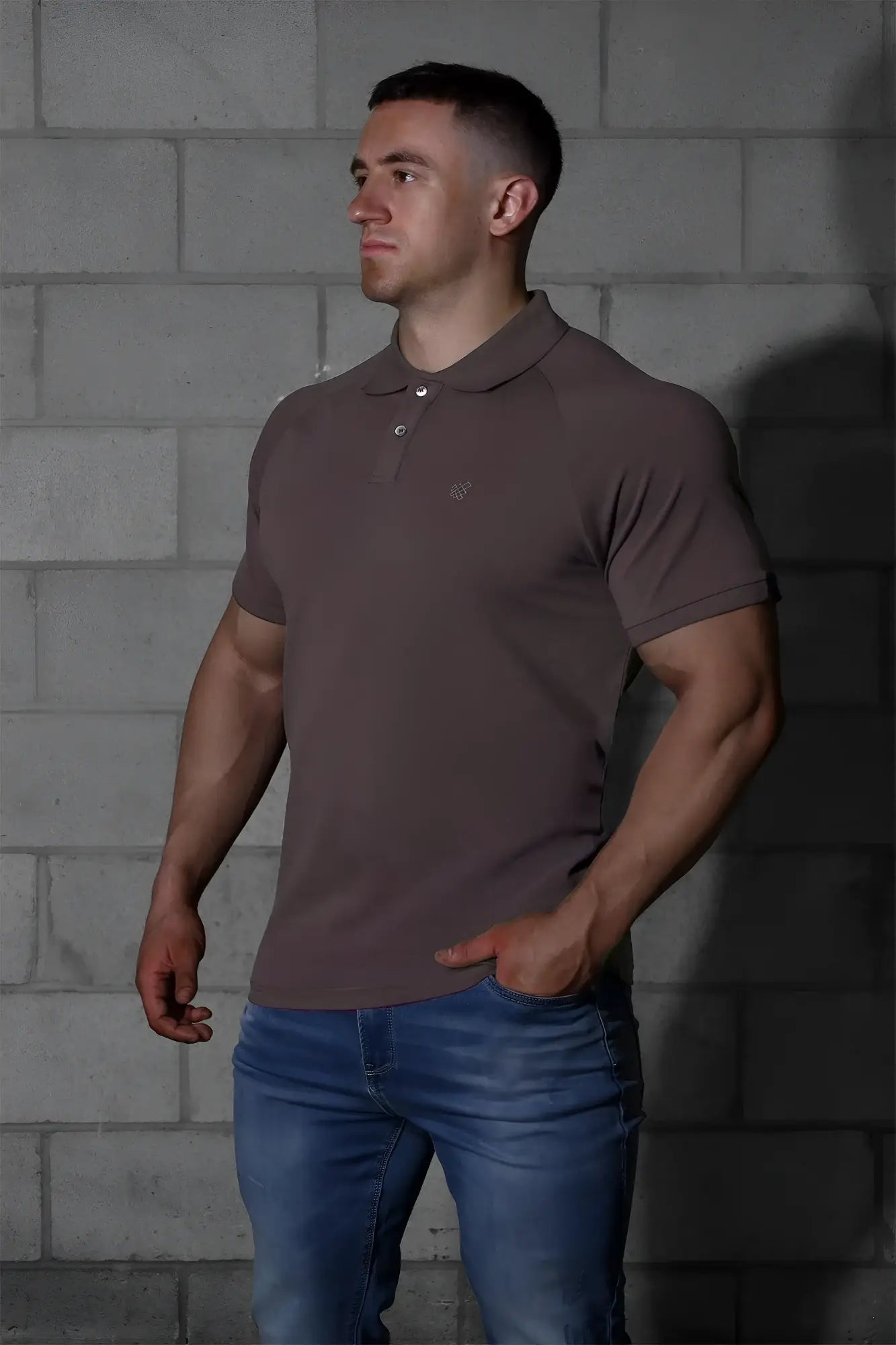 A man wearing a jed north muscle fit all day polo t shirt in dark gray with a small embroidered chest logo