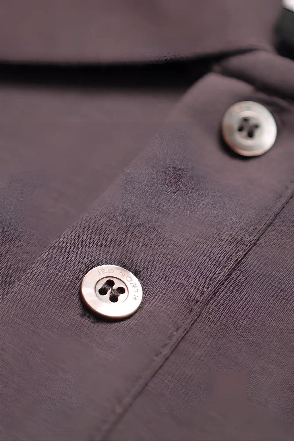 Silver-toned four-hole buttons engraved Jed Rogers on dark gray fabric of Jed North muscle fit all-day polo t-shirt