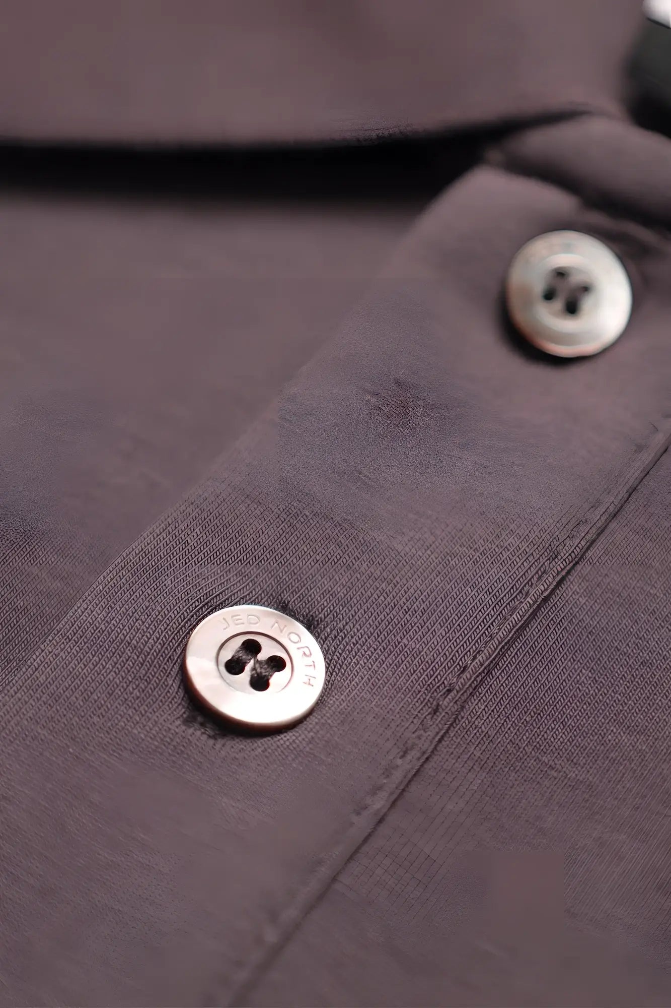 Silver-toned four-hole buttons engraved Jed Rogers on dark gray fabric of Jed North muscle fit all-day polo t-shirt