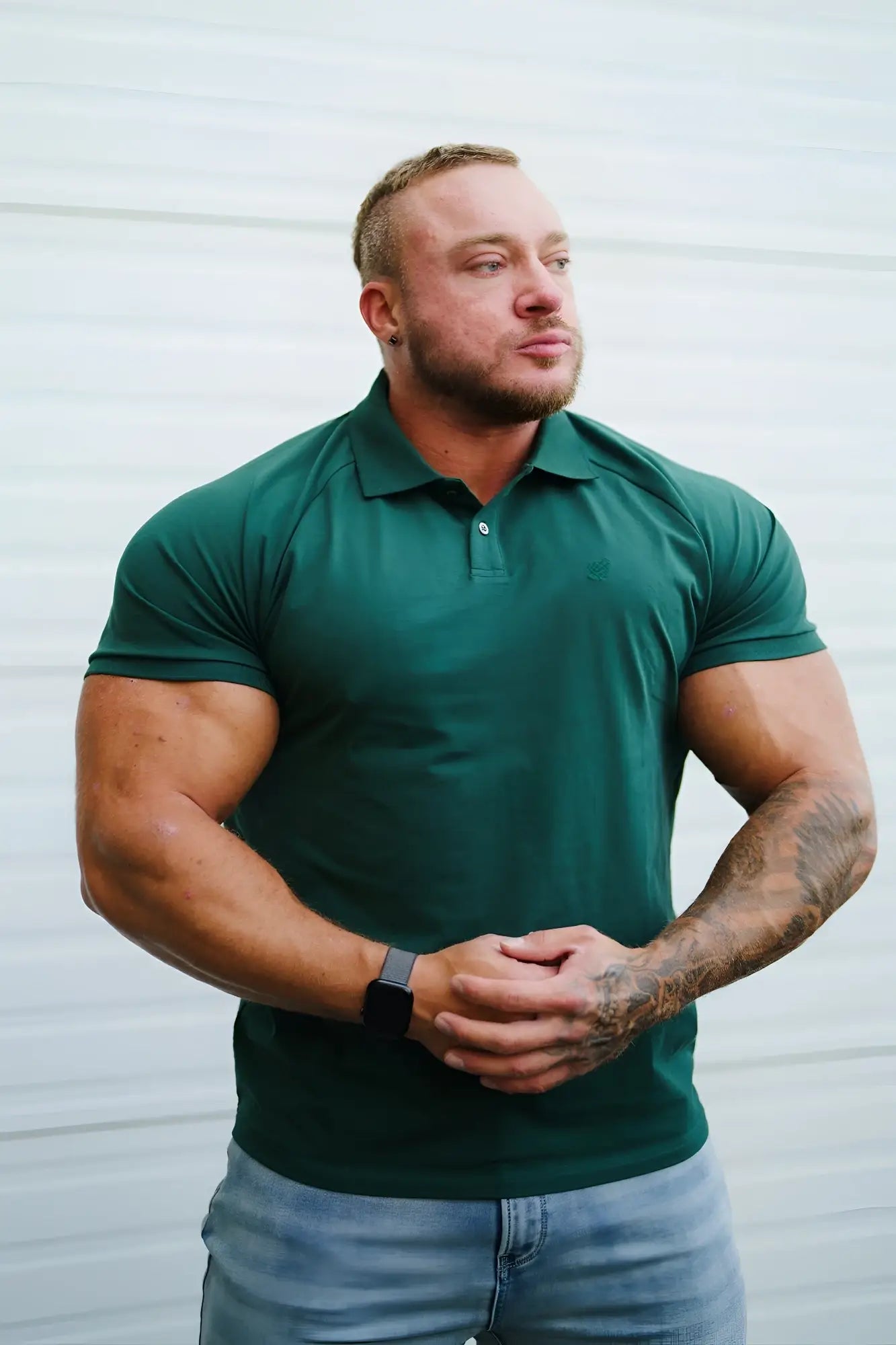 A man wearing a dark green muscle fit all-day polo shirt with short sleeves collar and buttoned placket