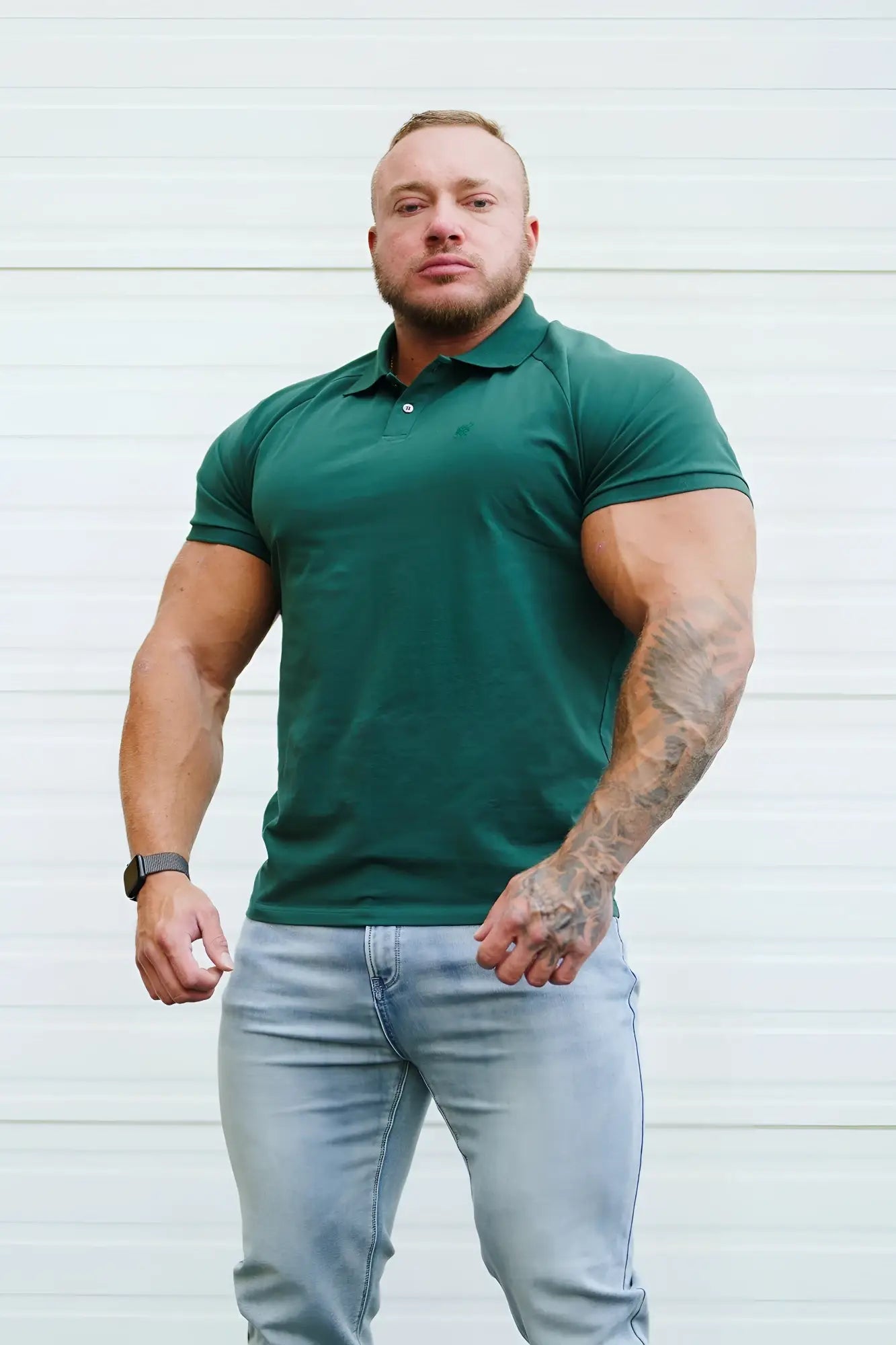 A man wearing a dark green muscle fit all-day polo t-shirt with short sleeves and button placket in evergreen
