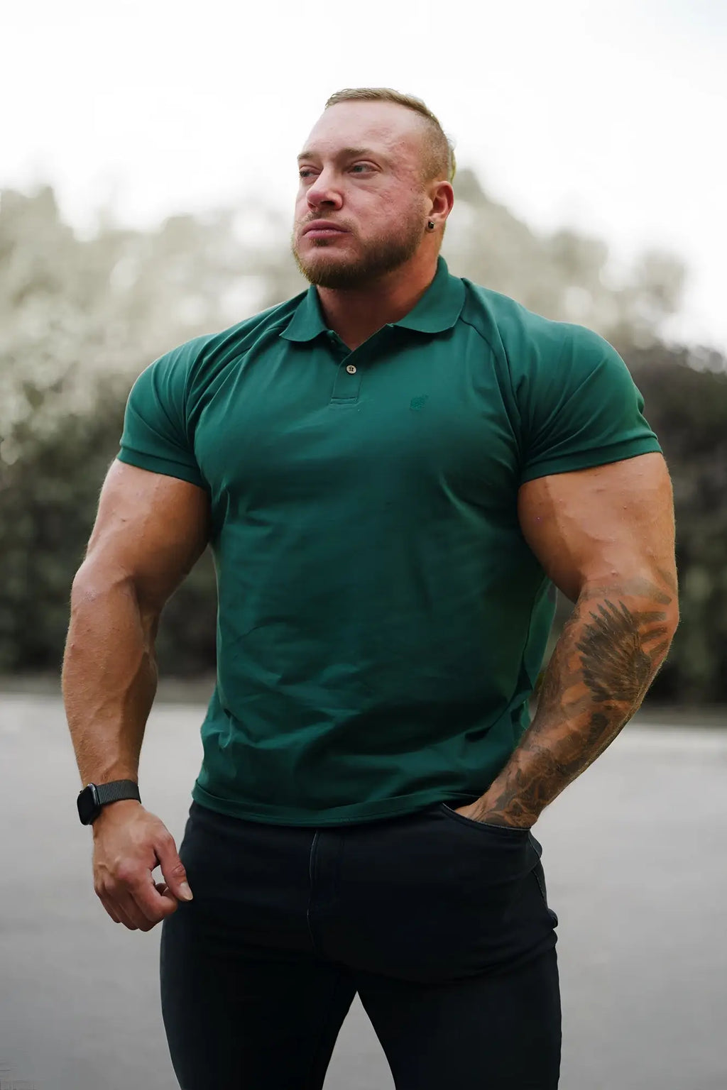 A man wearing a dark green muscle fit all-day polo t-shirt with collar and button placket in evergreen color
