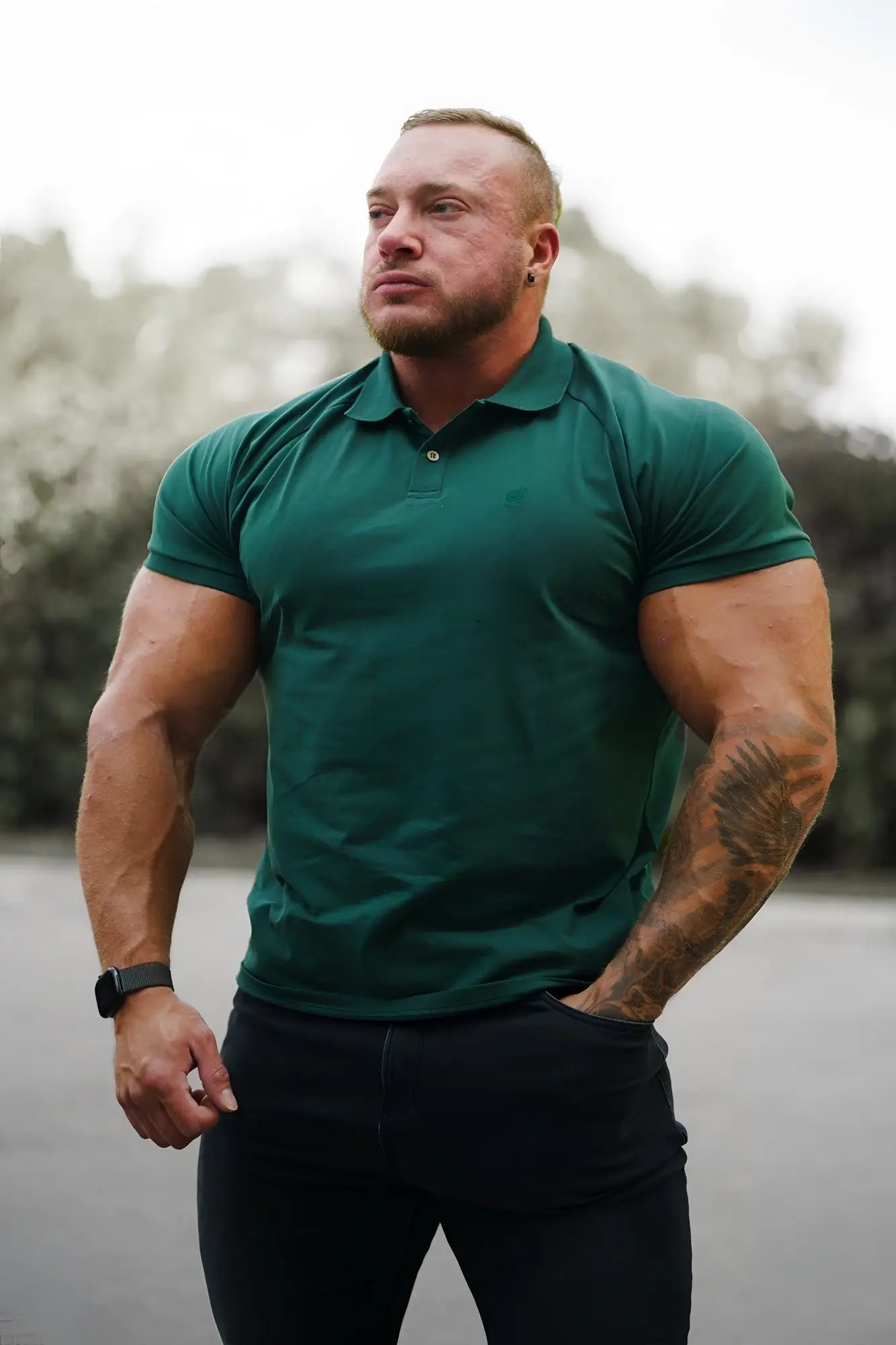 A man wearing a dark green muscle fit all-day polo t-shirt with collar and button placket in evergreen color