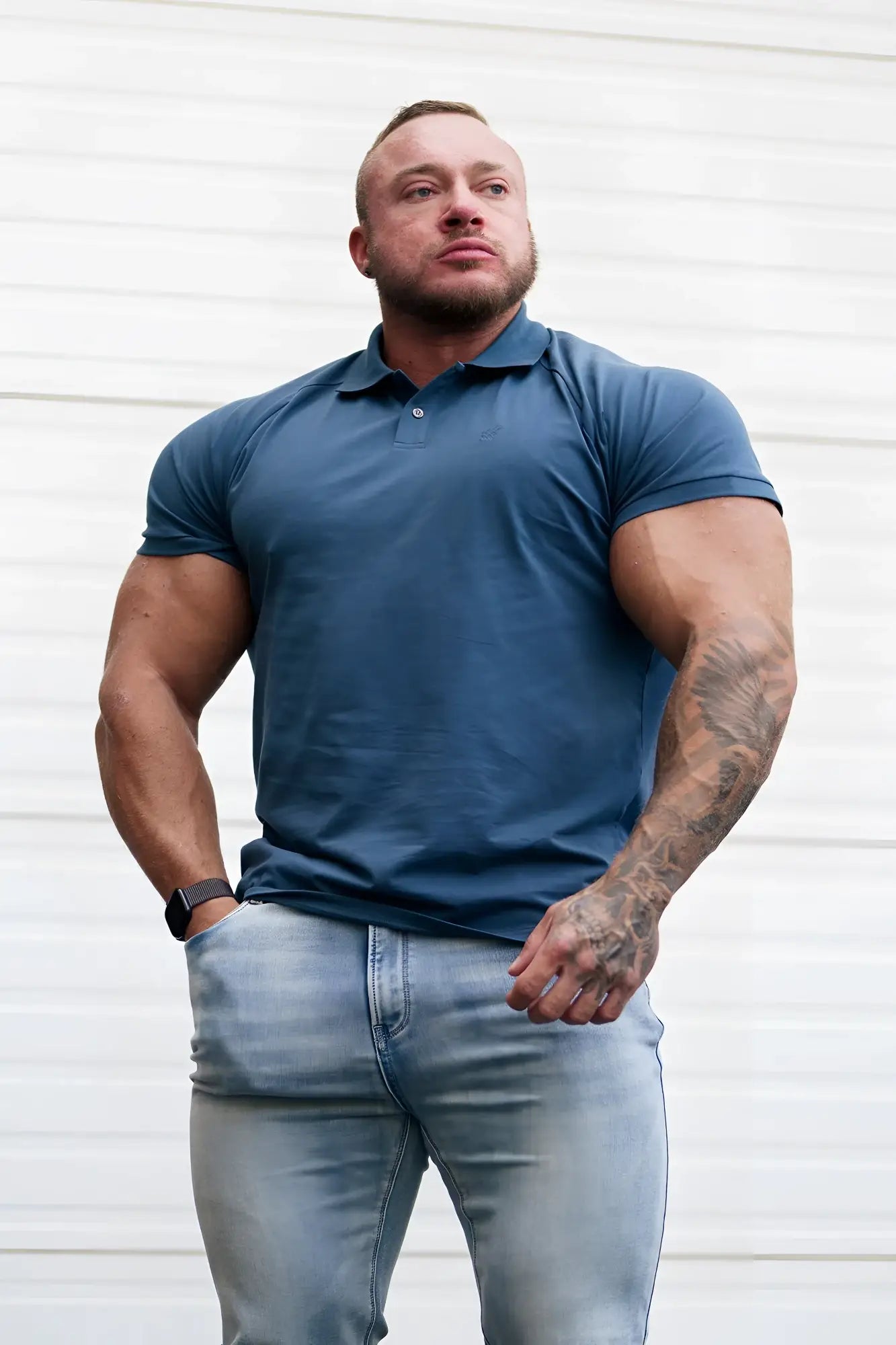 A man wearing a muscle fit all-day polo t-shirt in storm blue with short sleeves and a button placket collar