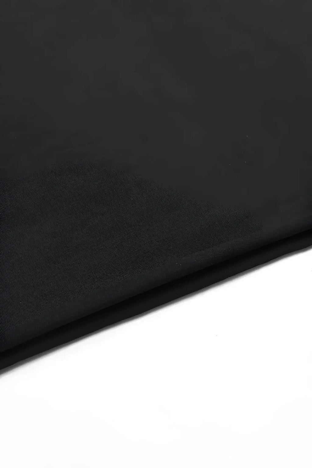 Black oversized raw-cut cropped tee fabric showing smooth slightly textured surface