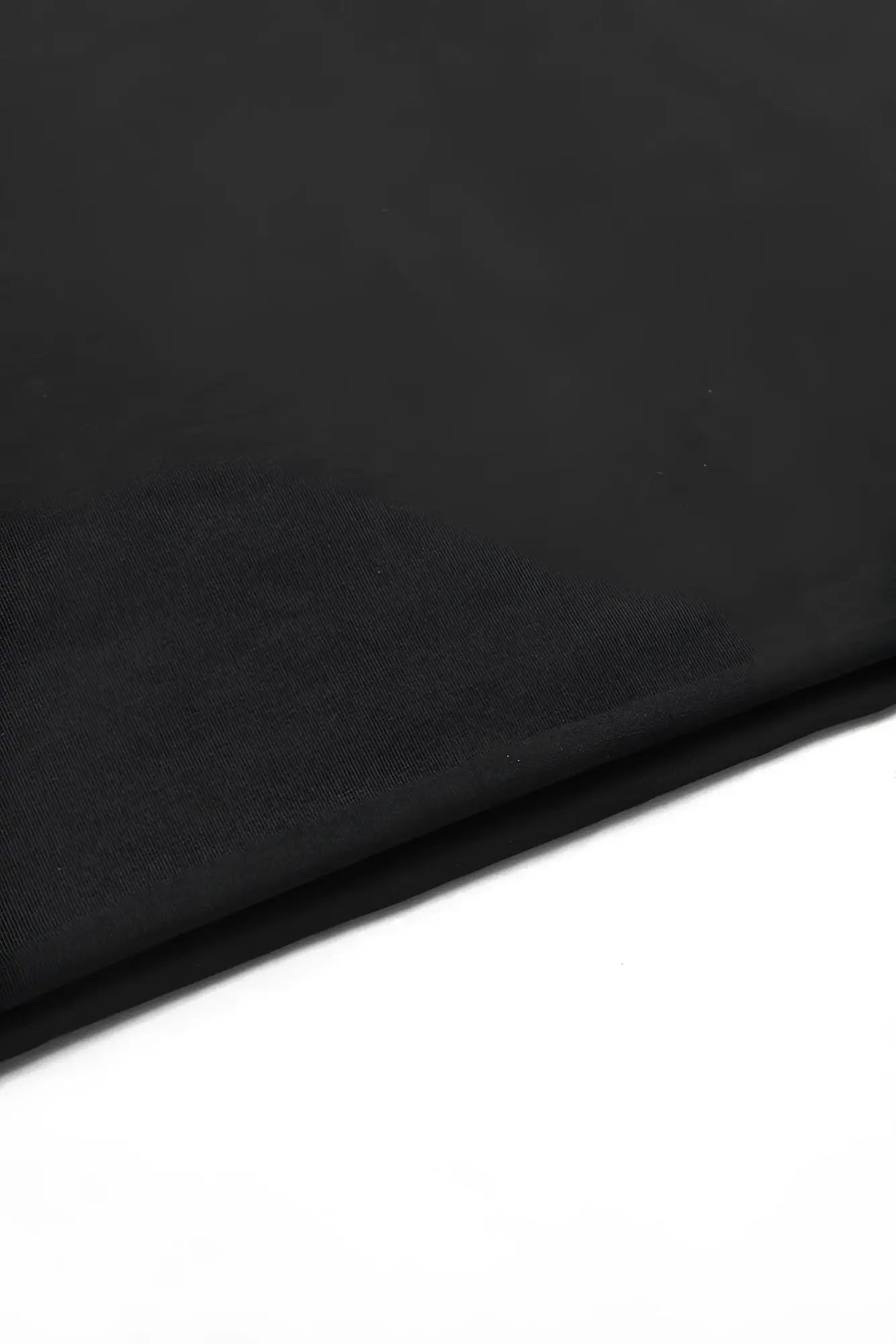 Black oversized raw-cut cropped tee fabric showing smooth slightly textured surface