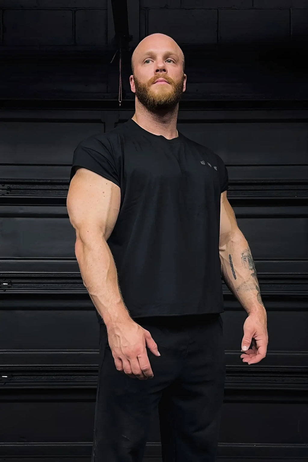 Black oversized raw-cut cropped tee with short sleeves and subtle chest logo ideal for athletic wear