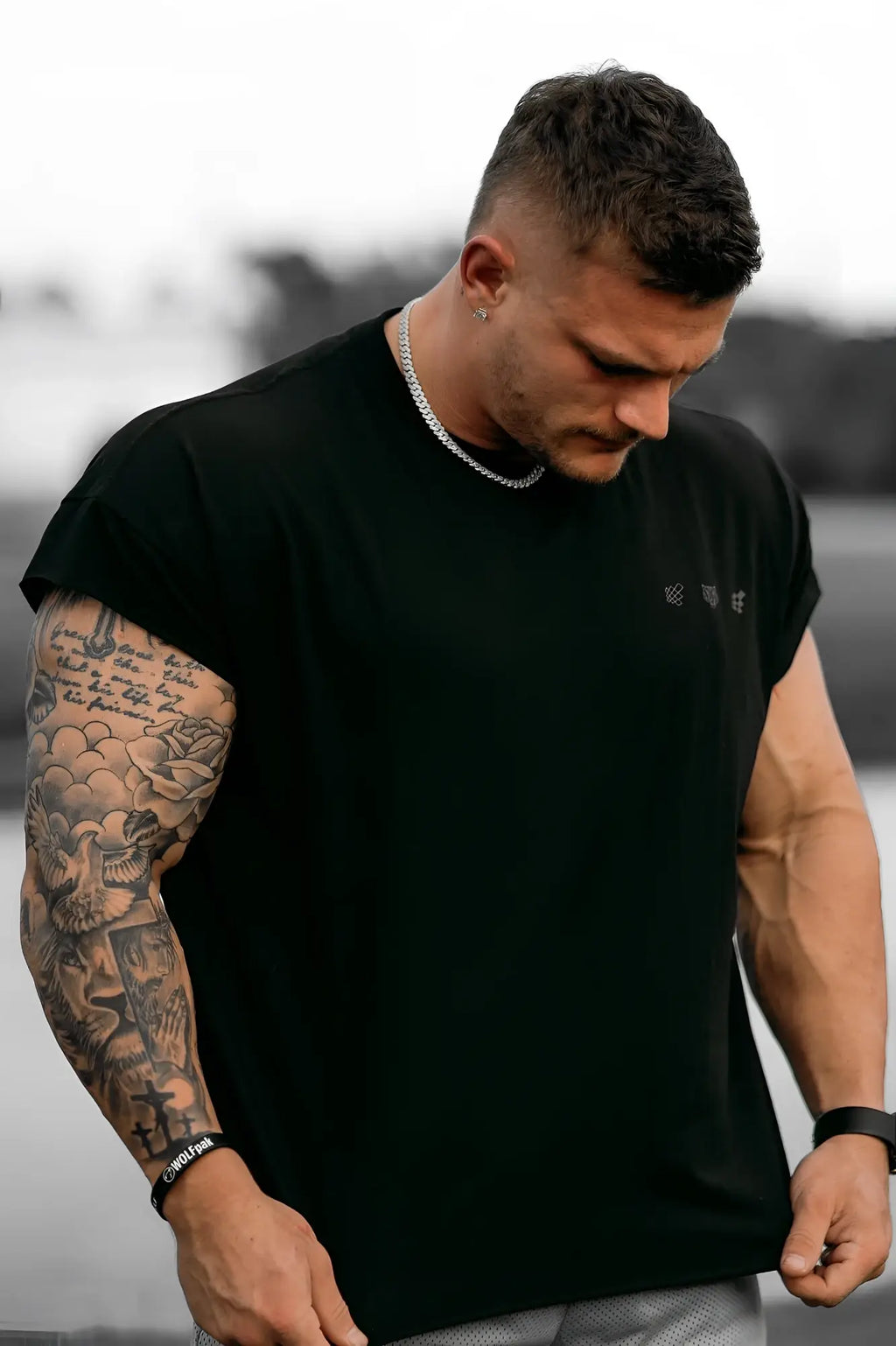 Black oversized raw-cut cropped sleeveless t-shirt with subtle embroidered logos on the chest in soft cotton