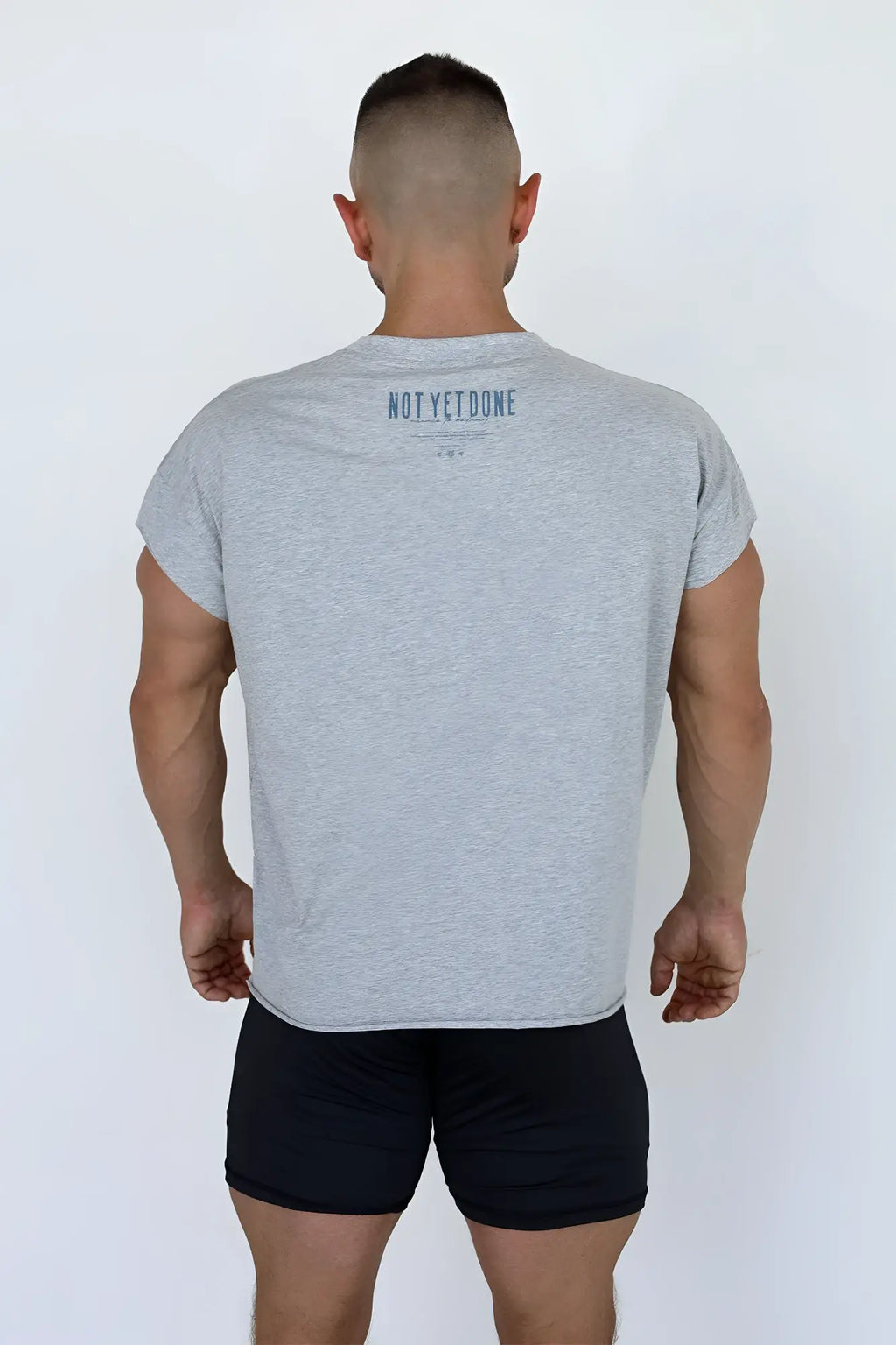 Back view of oversized raw cut cropped tee in heather gray with dark blue not yet done print on soft cotton blend