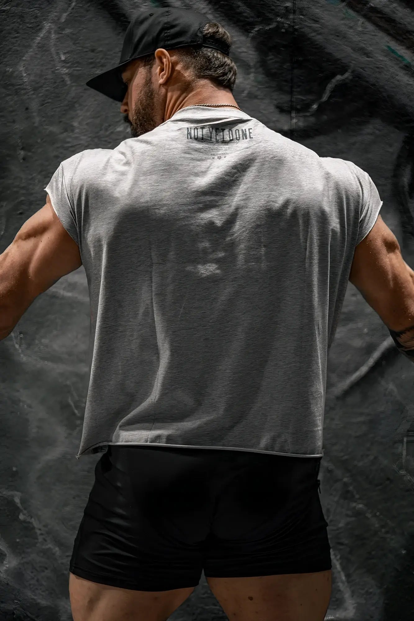 Back of oversized raw-cut cropped tee in heather gray sleeveless with not in loone printed on the back