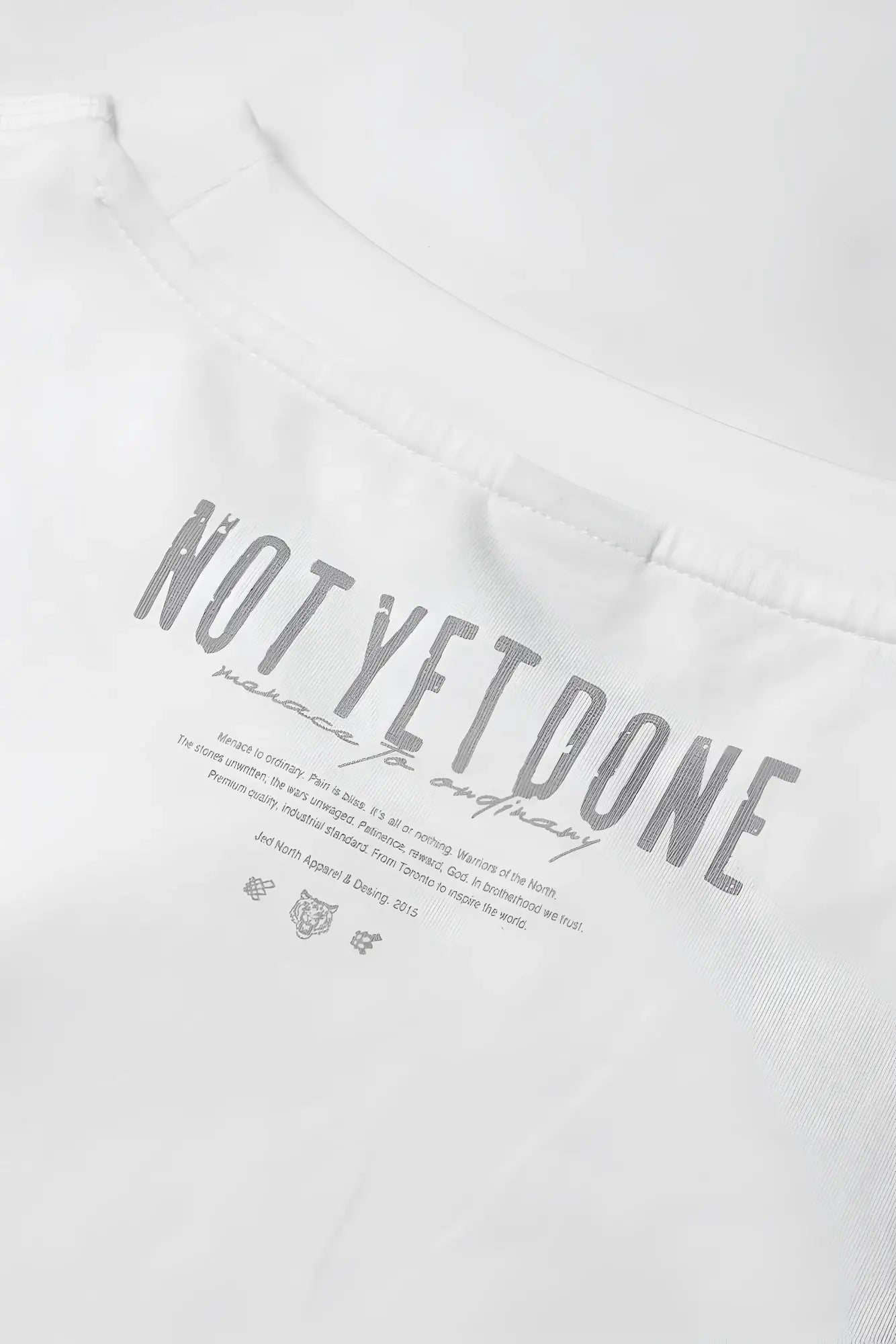 Oversized raw-cut cropped white cotton tee with gray not yet done text and smaller print below on front