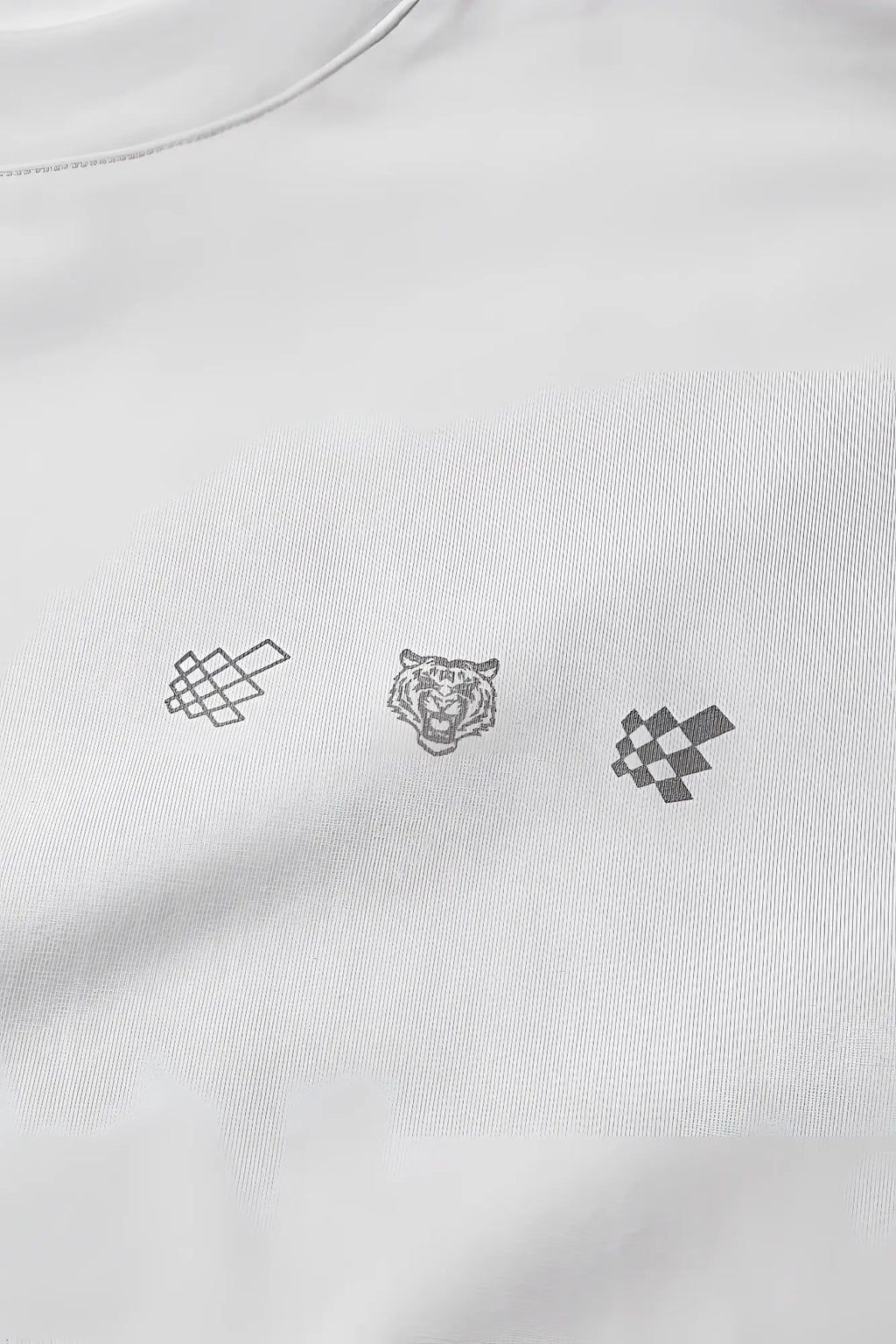 White oversized raw-cut cropped cotton tee with three minimalist embroidered logos of a knot, tiger head, and checkered flag