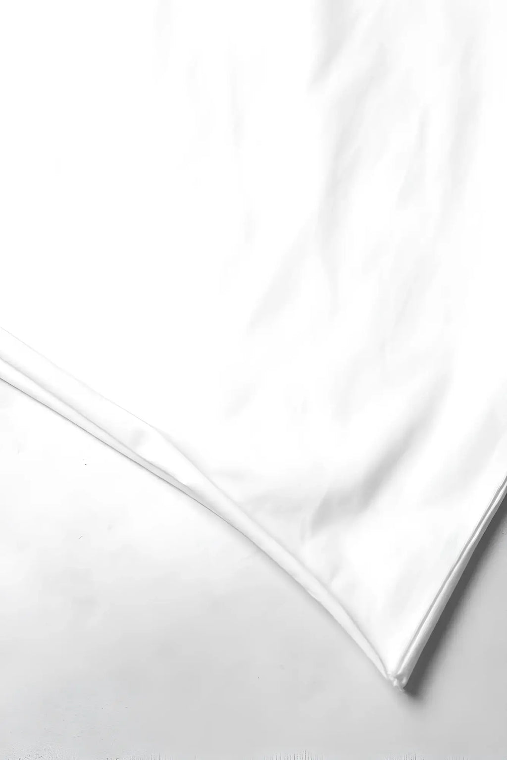 A crisp white silk pillowcase with smooth reflective surface and neatly finished edges displayed with an oversized raw-cut cropped tee white